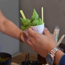a person holding a cup filled with green food