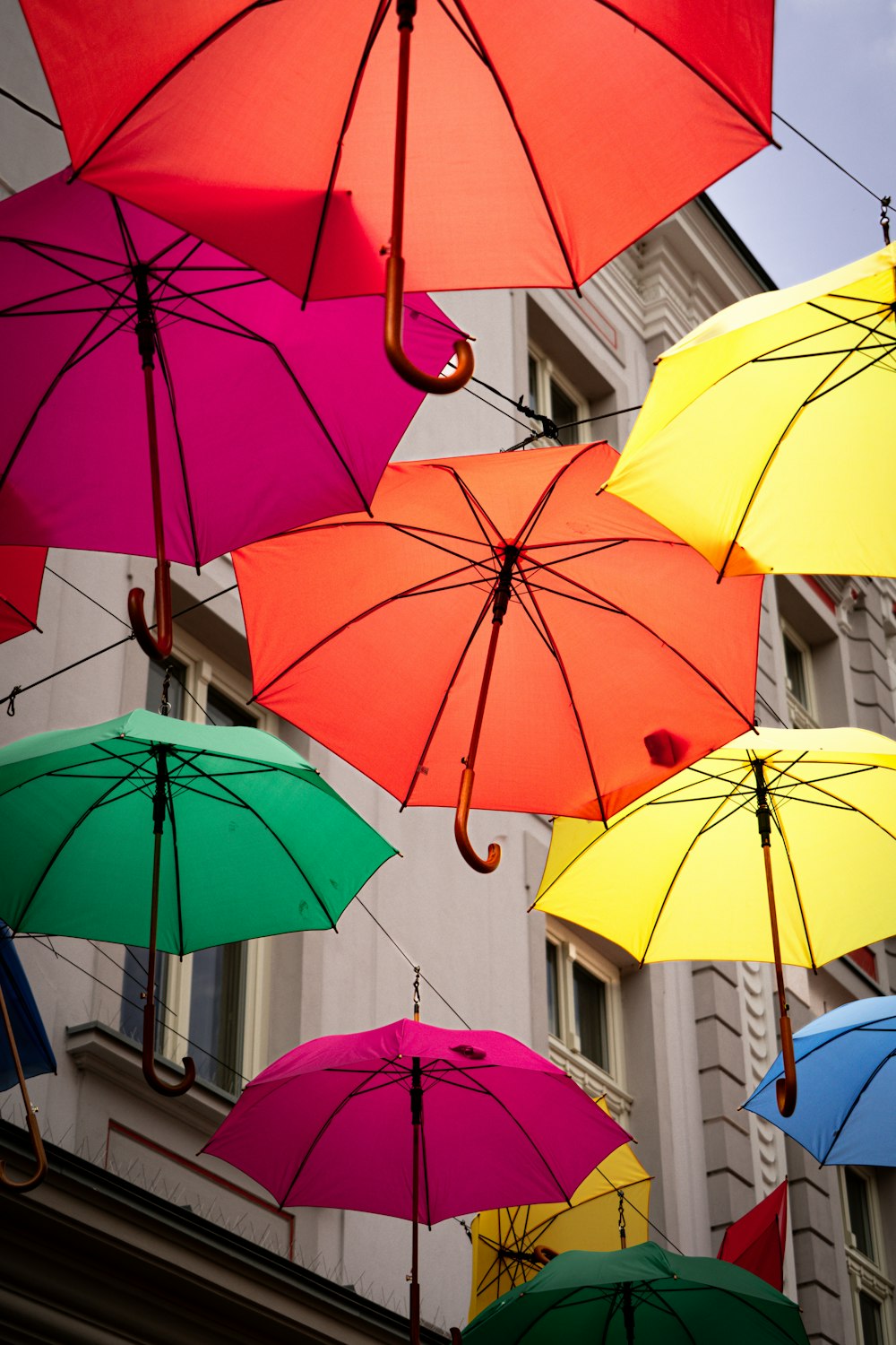 a group of multicolored umbrellas hanging from a building