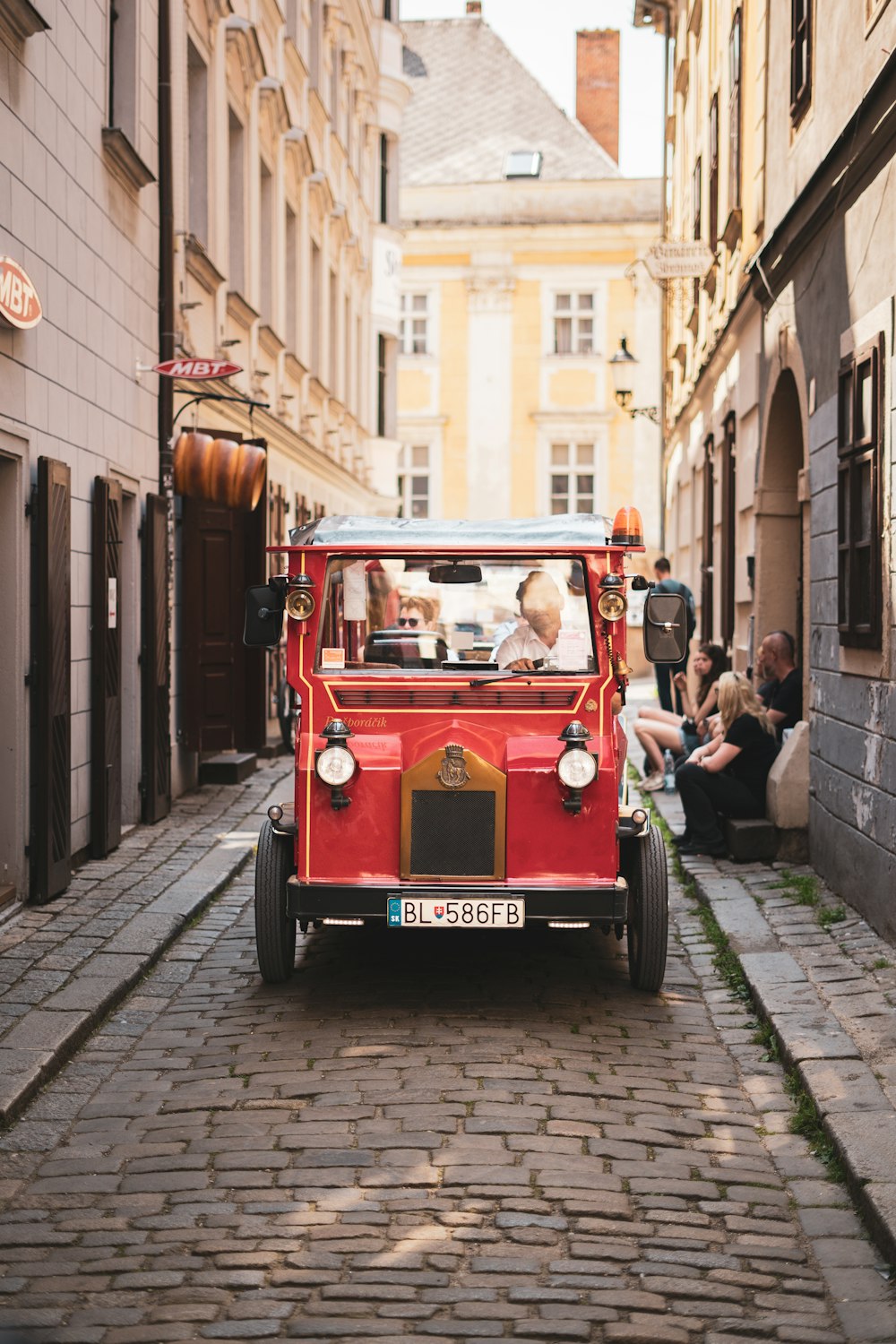 a small red car driving down a cobblestone street