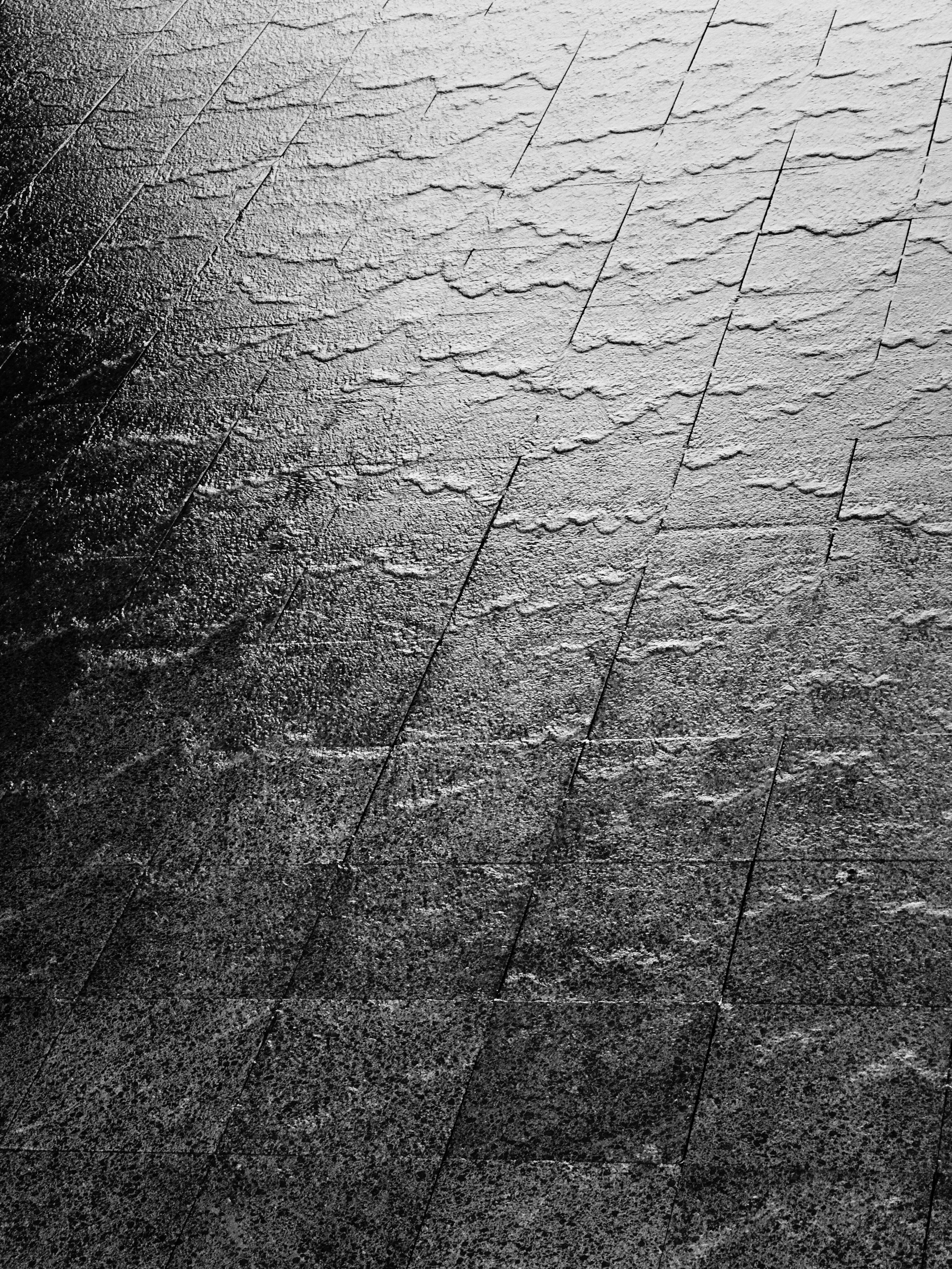 Textured stone-look floor tiles in a contemporary commercial space, dramatic low-angle lighting, deep shadows