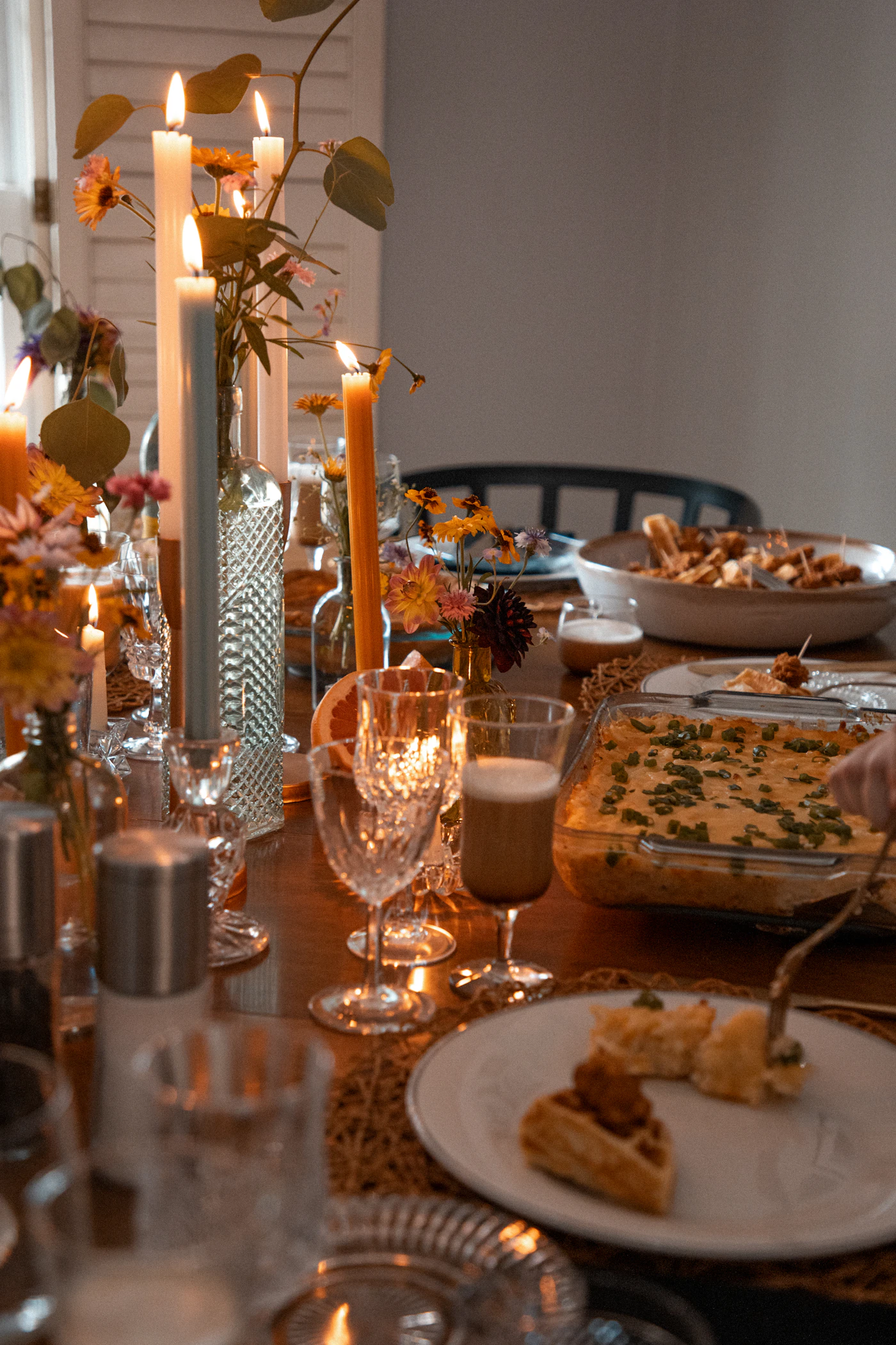 Long dinner table set with candles and plates in a warm room