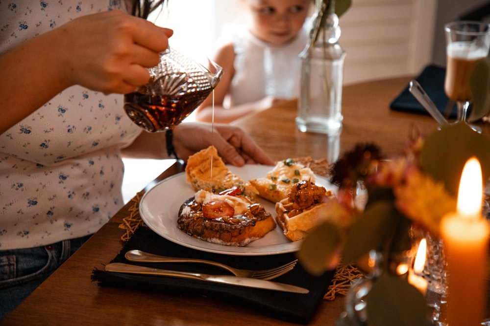 a woman pouring tea over a plate of food