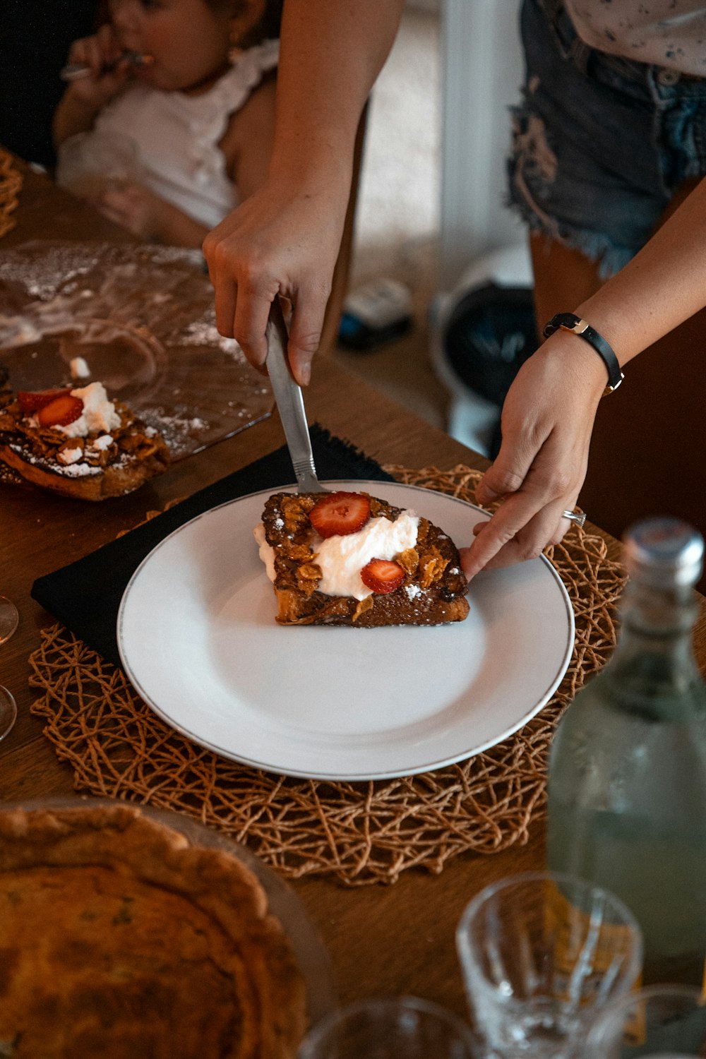 a woman cutting a piece of cake on top of a white plate