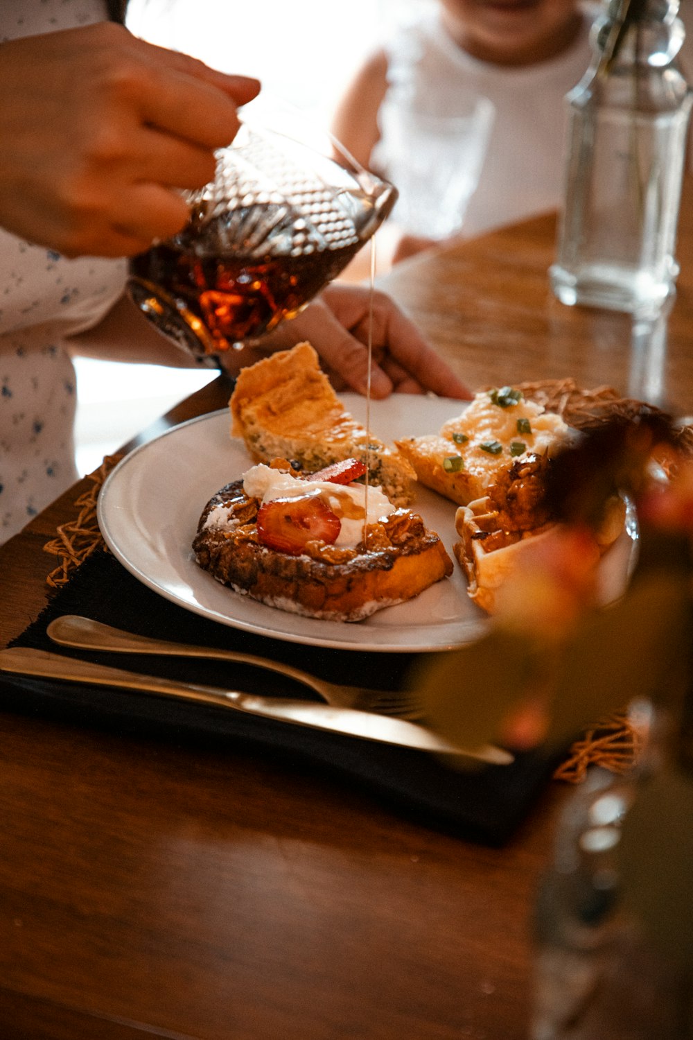 a person pouring syrup on a plate of food