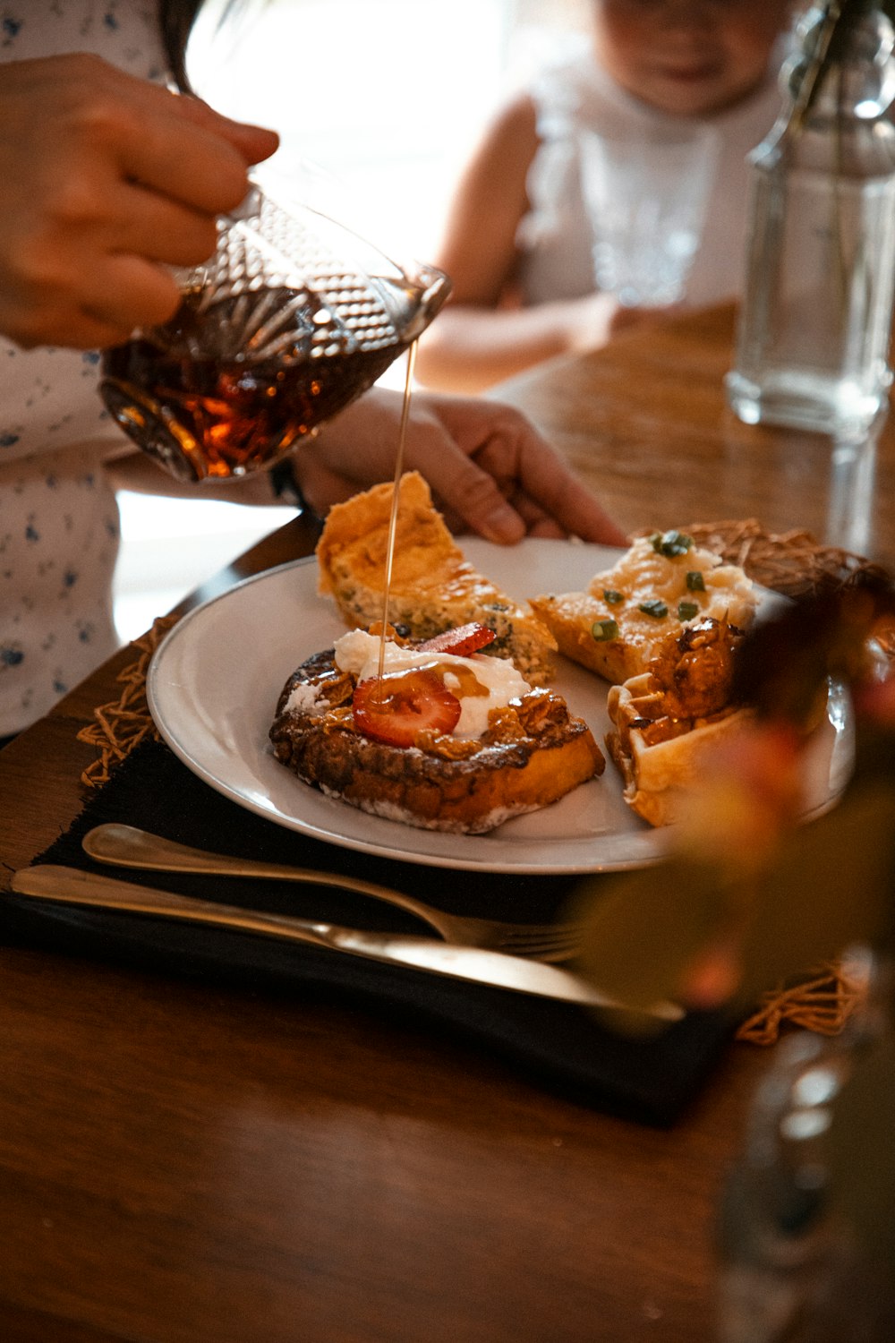 a person pouring syrup on a plate of food