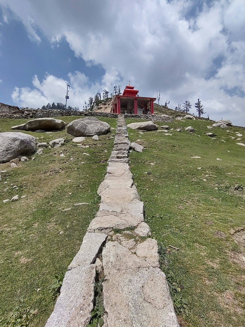 a stone path leading to a red building on top of a hill