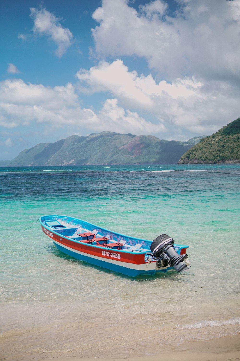 a blue and red boat sitting on top of a beach