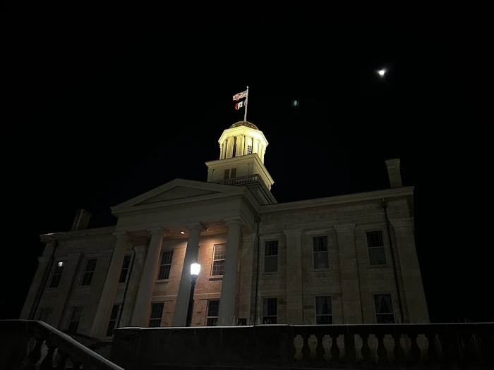 Clock tower building lit up at night in Iowa City, a university town where many members are online