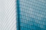 A modern skyscraper with reflective glass panels aligned in a geometric pattern, showcasing a sleek and contemporary architectural design. The building facade curves smoothly, adding an element of elegance and sophistication.