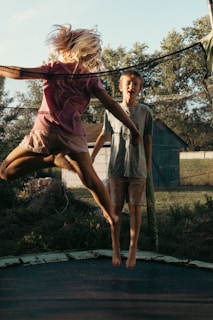 A child mid-air performing a joyful jump on the trampoline with a big smile.