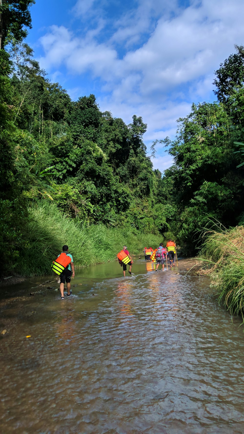 a group of people walking across a river