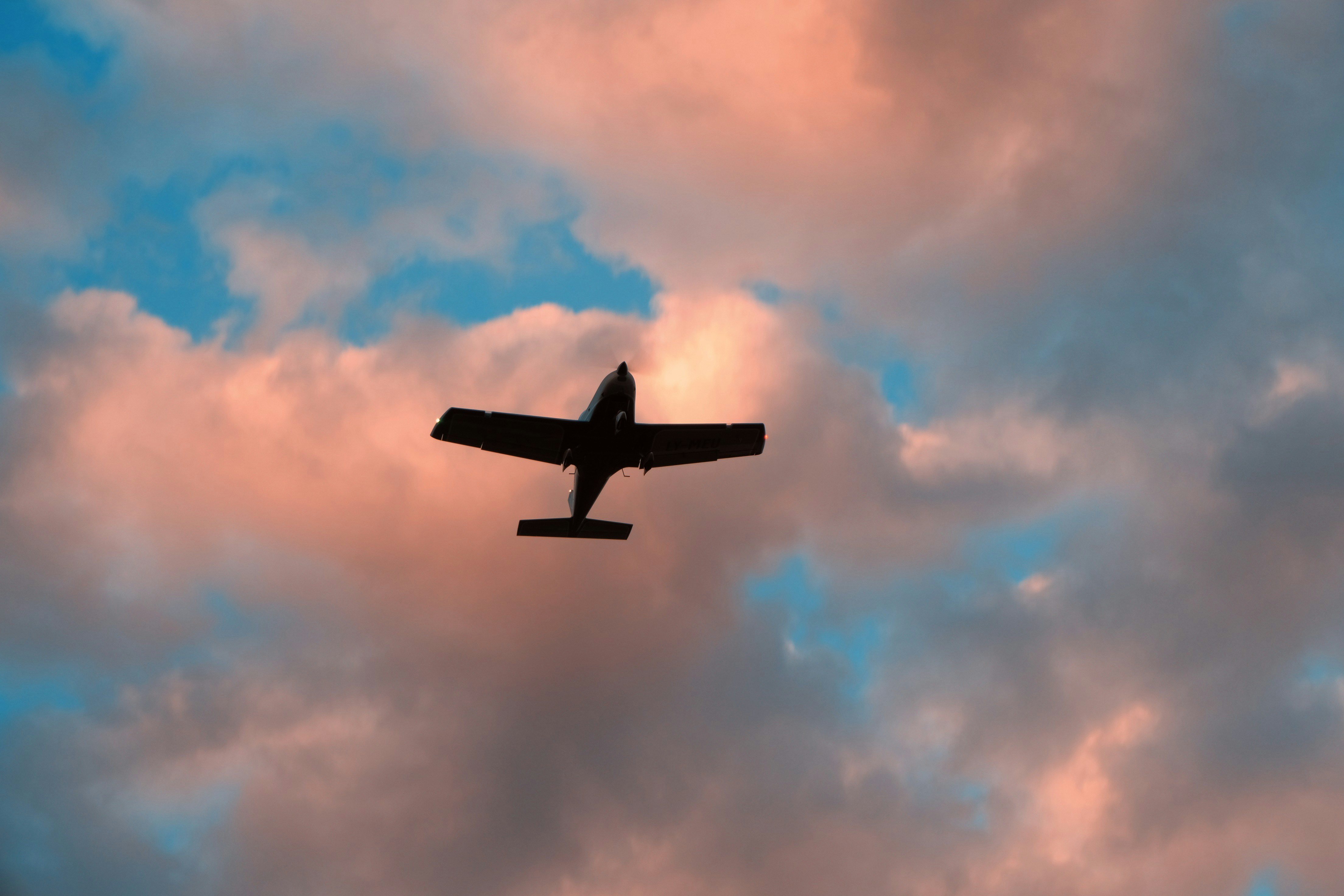 A small plane in silhouette against pinkish sunset clouds.