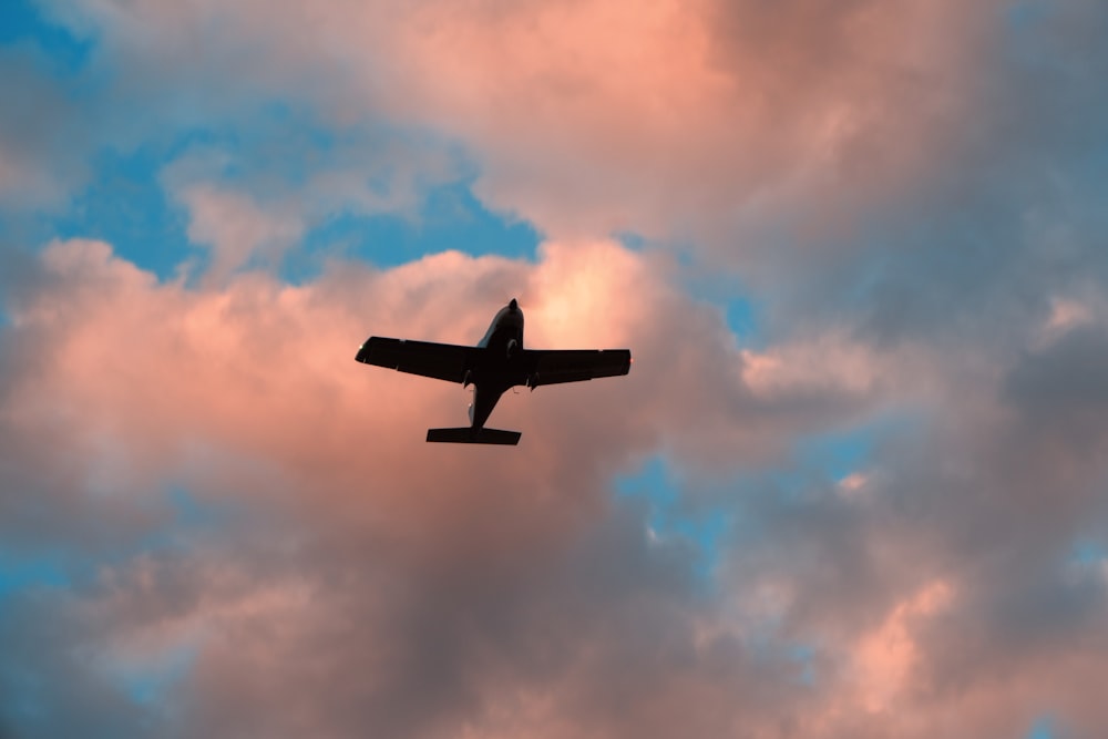 a plane flying through a cloudy blue sky