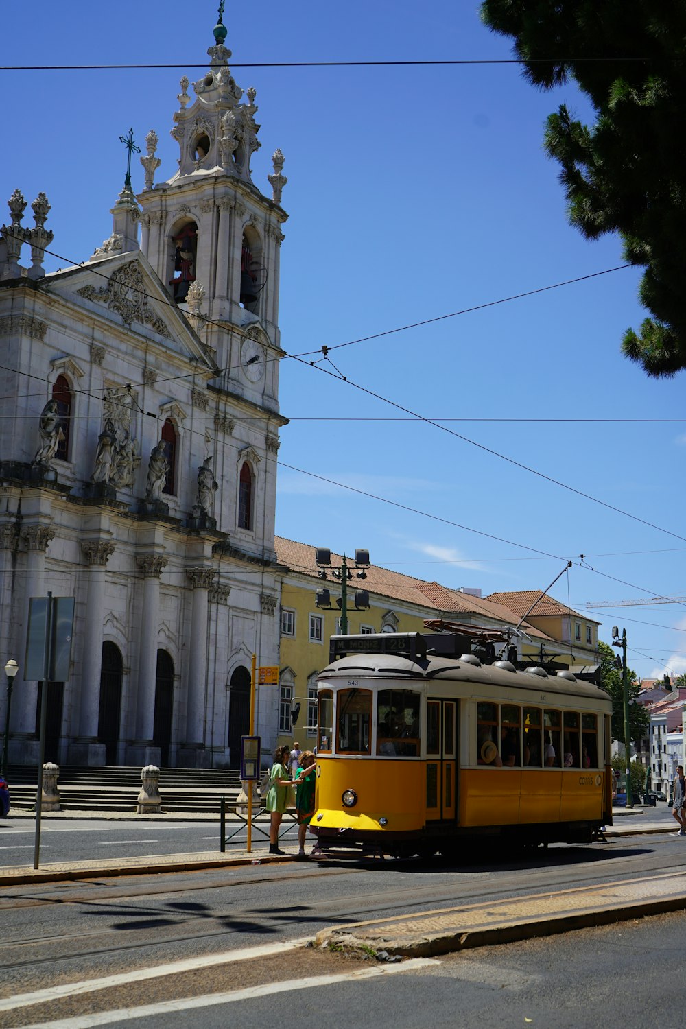 a yellow trolley is going down the street in front of a church