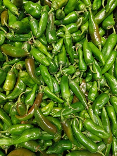 Fresh green chilies neatly arranged in a rustic wooden crate.