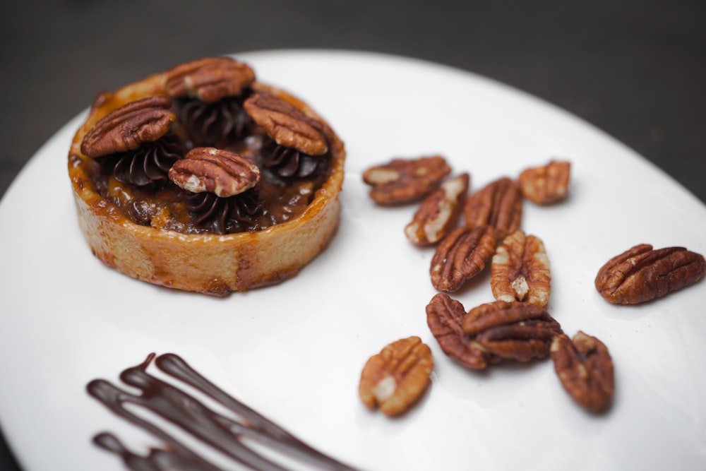 a white plate topped with a pastry covered in pecans