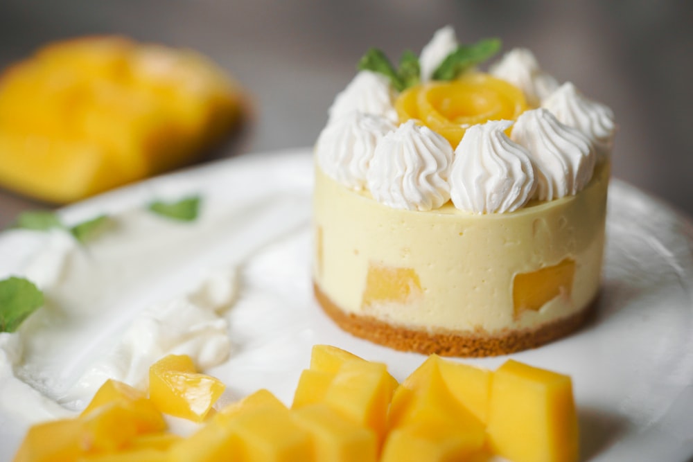 a cheesecake topped with whipped cream and mango slices