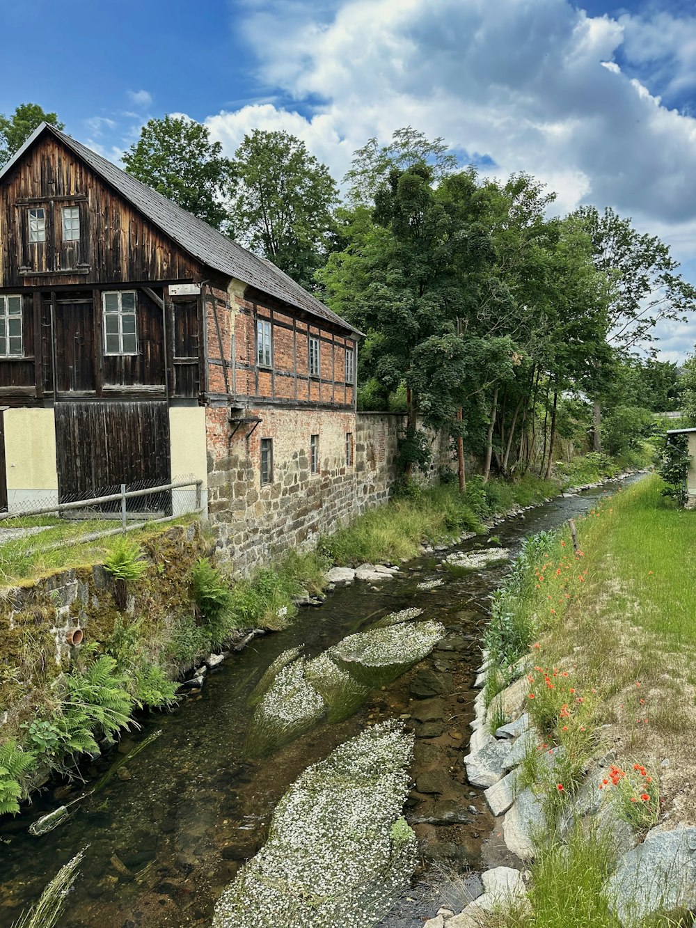 ein Holzgebäude, das neben einem Fluss sitzt