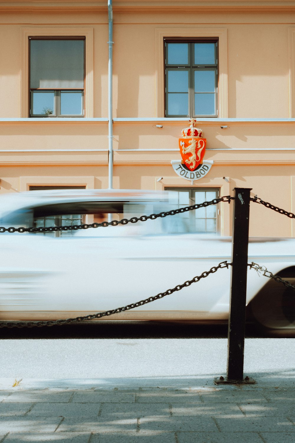 a white car driving past a tall building