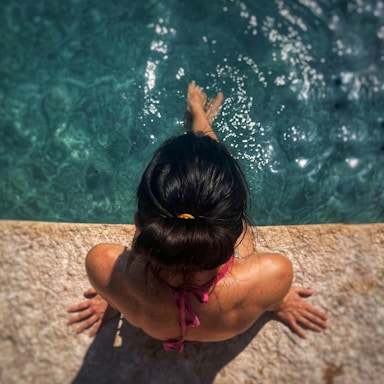 a woman in a pink bikini standing next to a swimming pool