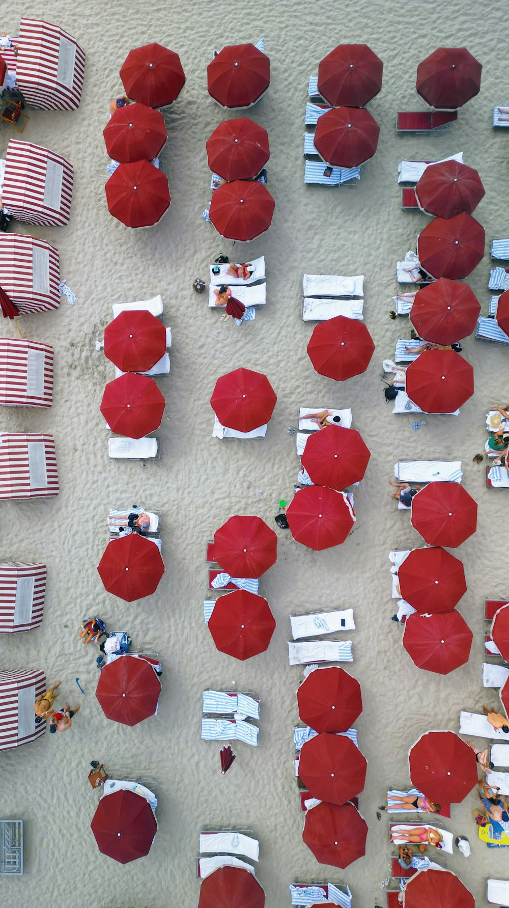 a group of red umbrellas sitting on top of a sandy beach