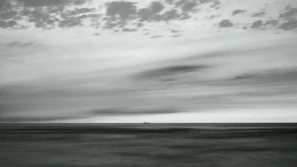 Historic photo of the ship sailing through rough seas with dramatic clouds overhead