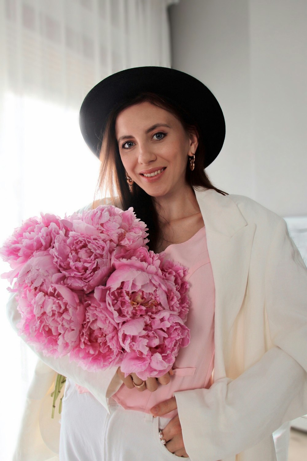 a woman in a hat holding a bouquet of flowers