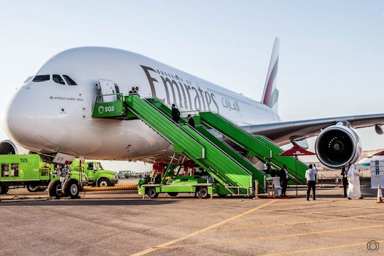 A team of ground crew members in uniform assisting passengers near an aircraft.