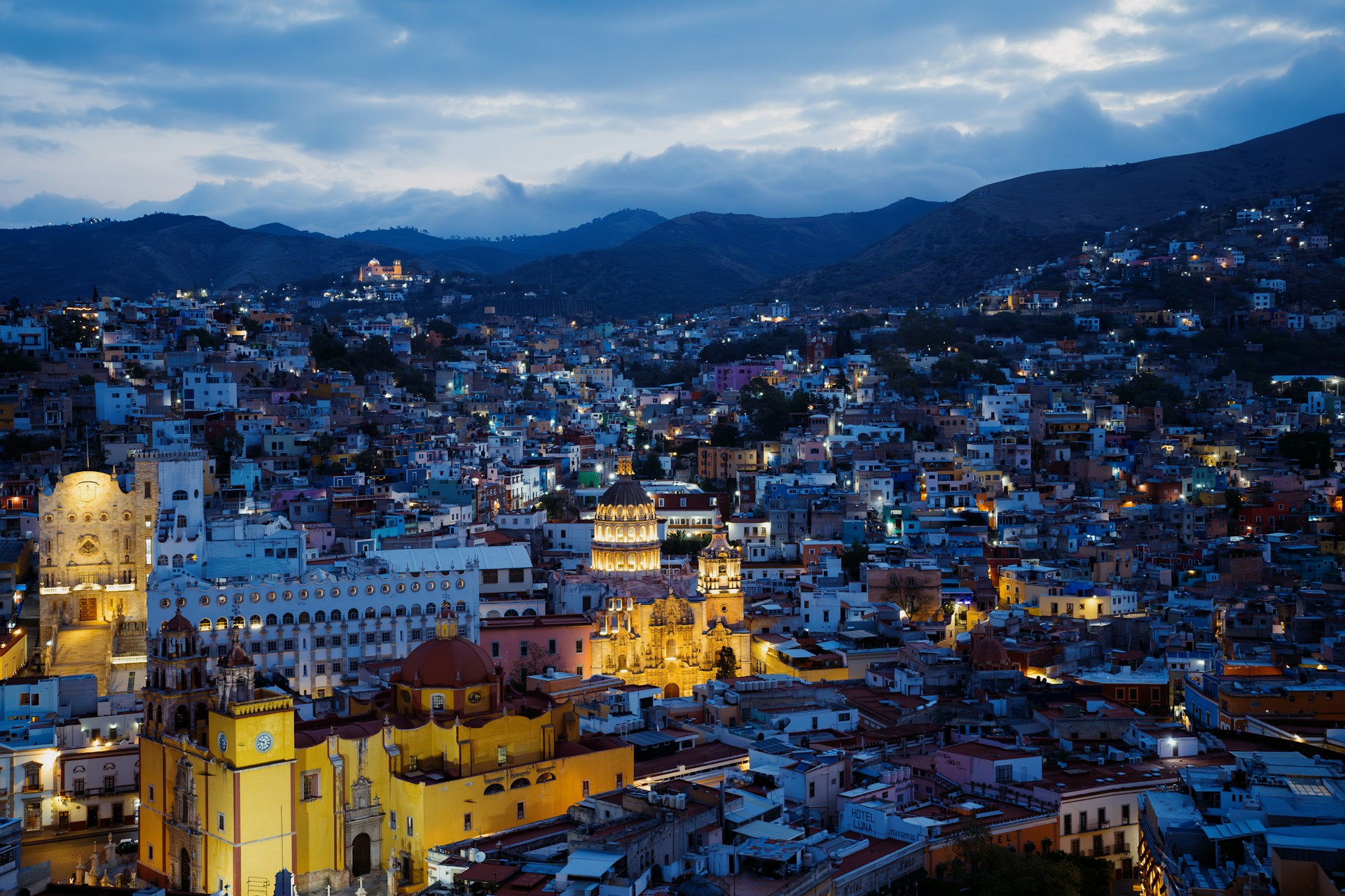 a view of a city at night with mountains in the background