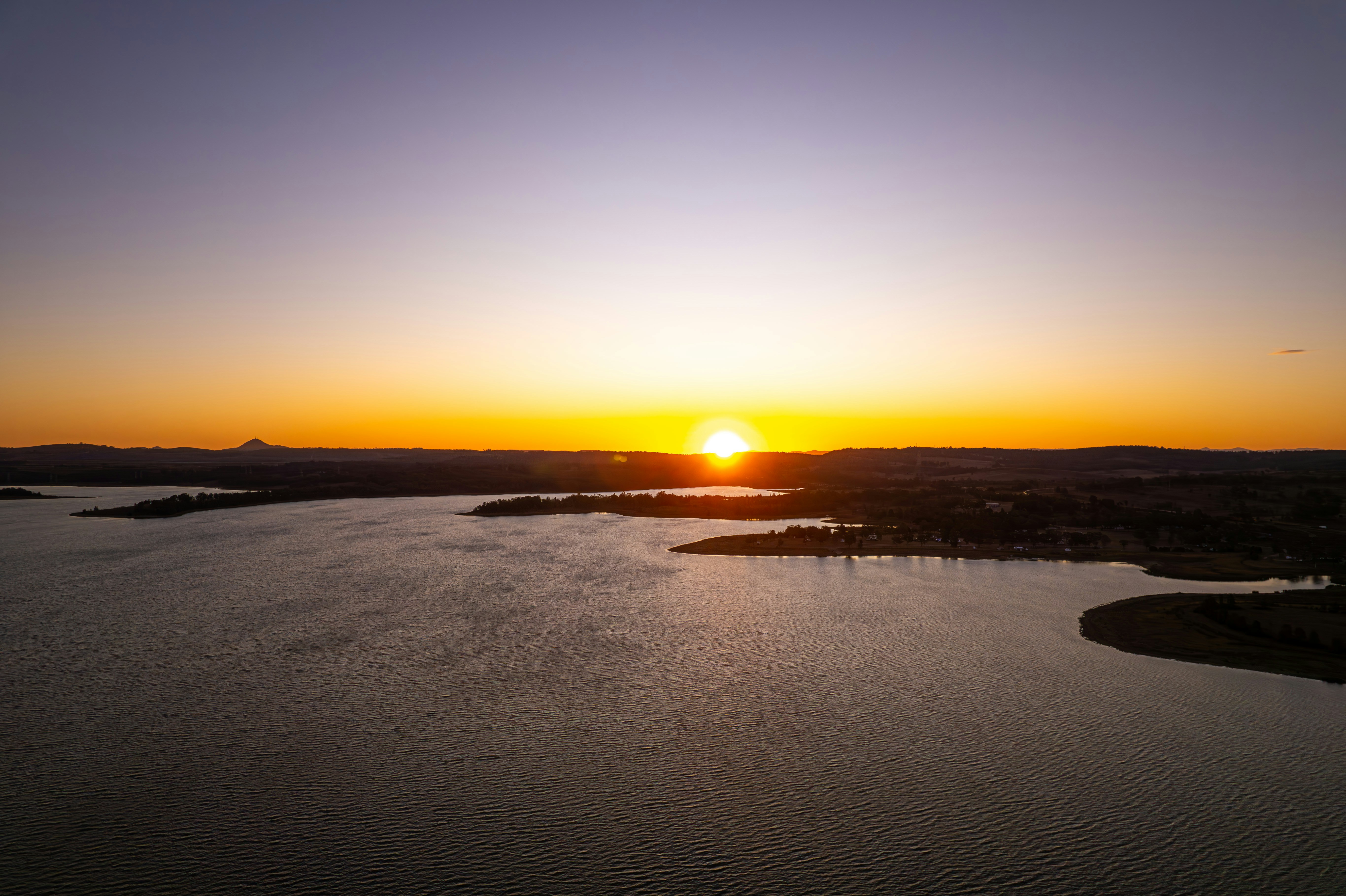 Soft warm sunrise over gentle hills, golden hour light, calm open sky with subtle warmth