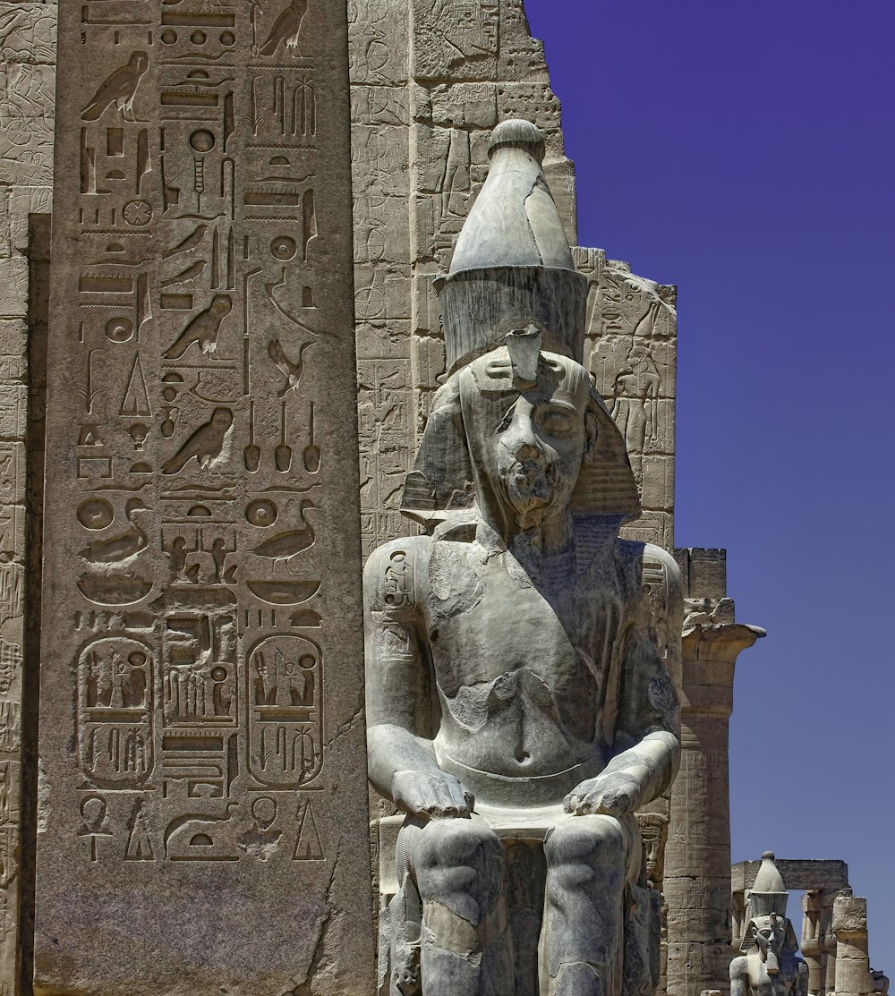 a statue of an egyptian god in front of an egyptian temple