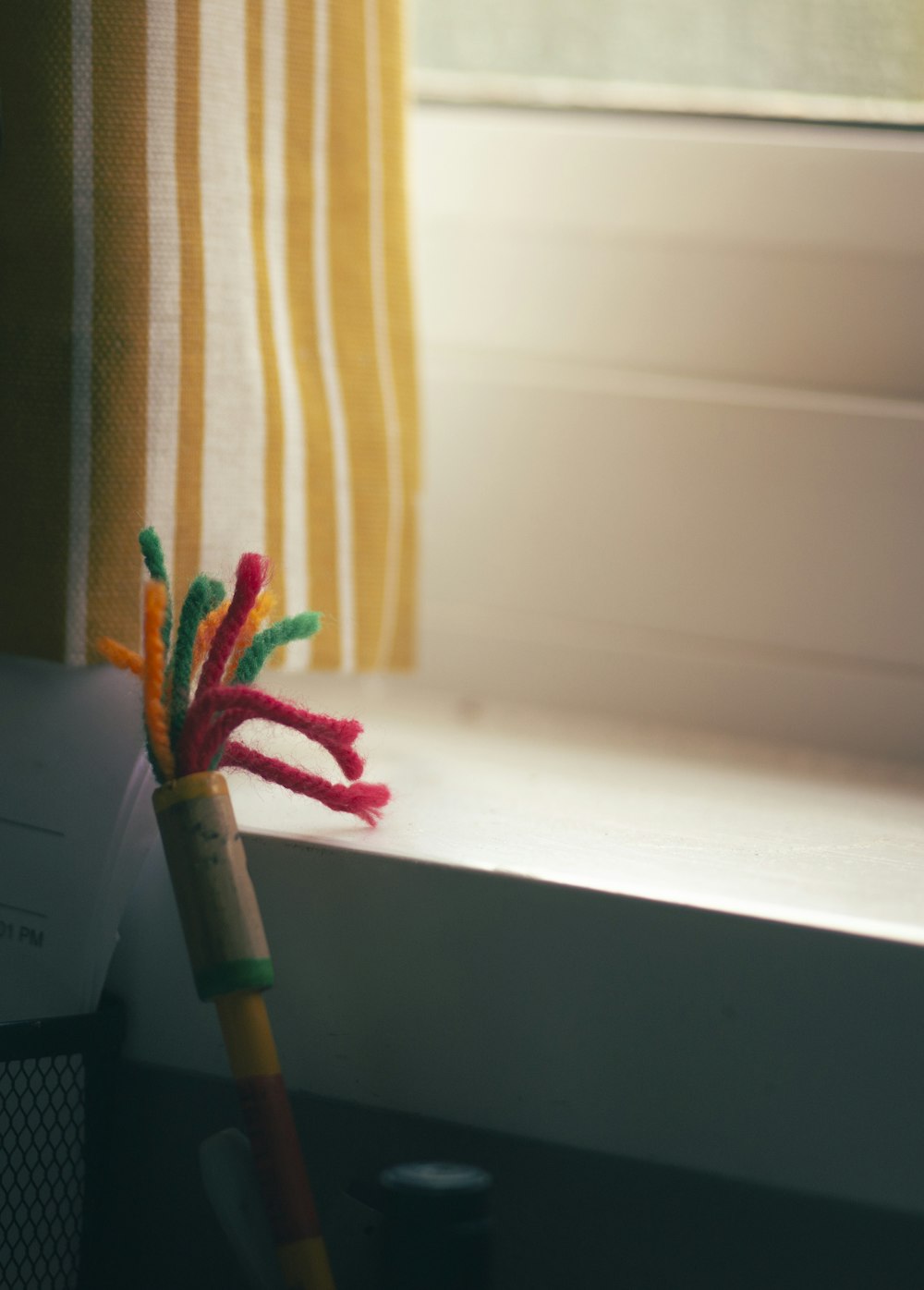 a pencil and some yarn on a window sill