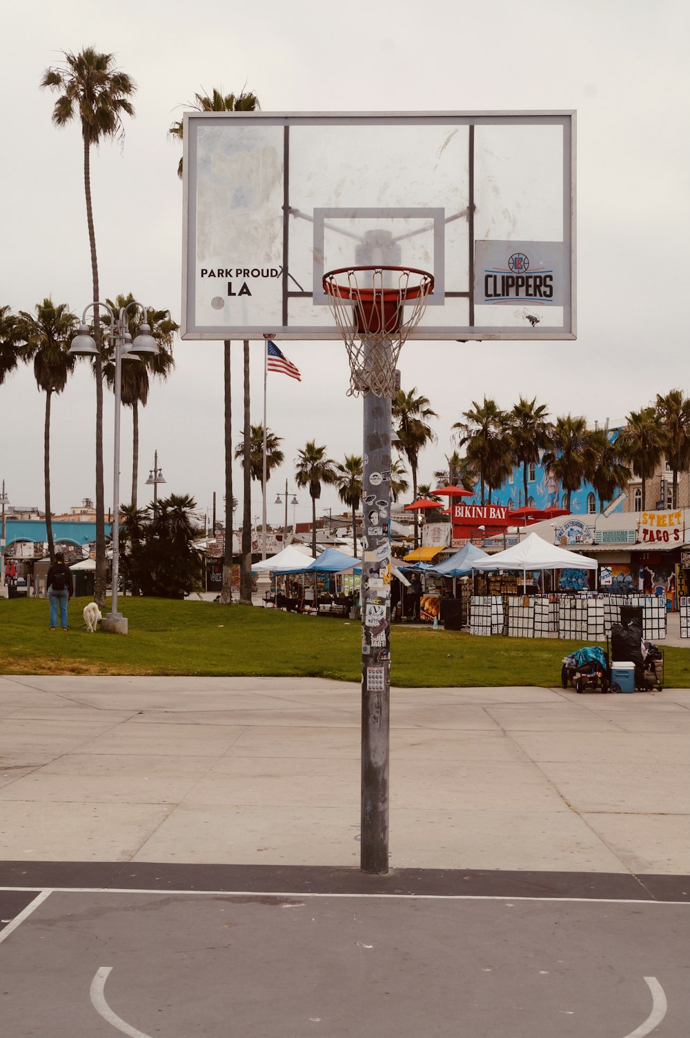 Un aro de baloncesto en un aparcamiento con palmeras al fondo