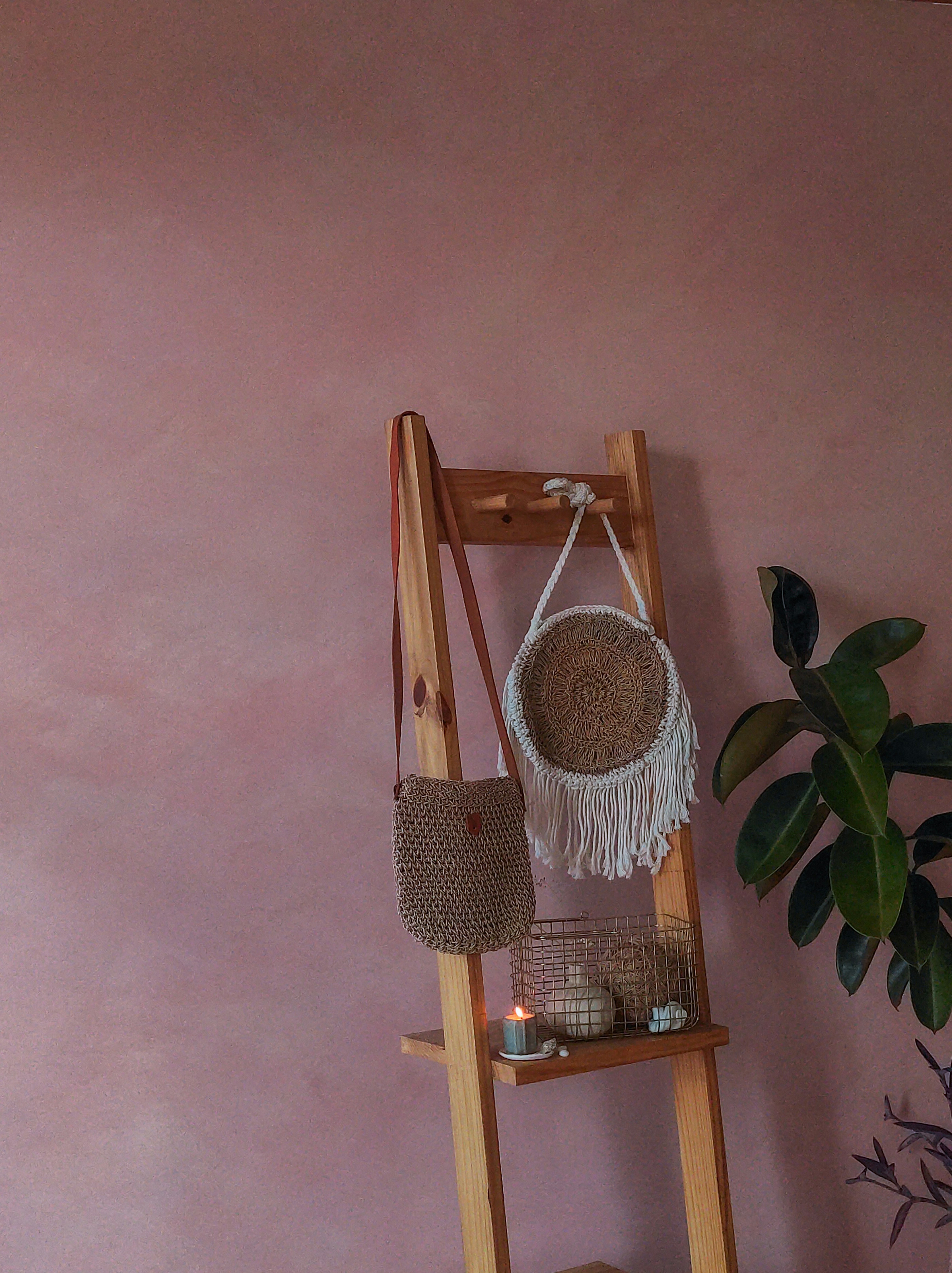 Two woven bags hang on a rustic wooden ladder.