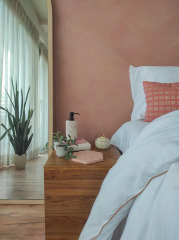 a bedroom with pink walls and a bed with white sheets
