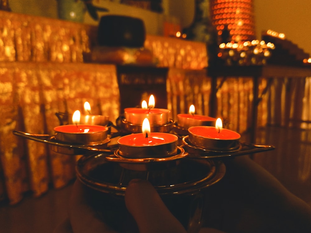 a person holding a tray of lit candles