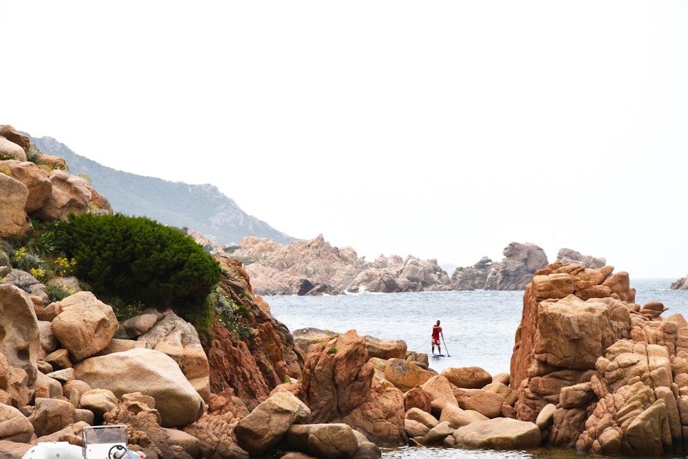 a person on a surfboard in the water near rocks