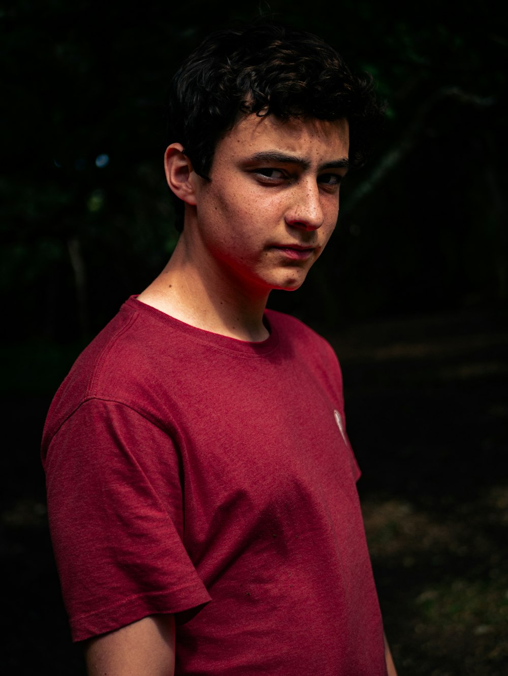 a man in a red shirt standing in the dark