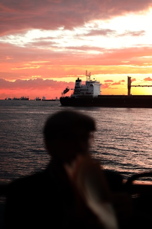 An inspiring sunset view of a large cargo ship sailing on the open sea, symbolizing career journeys.