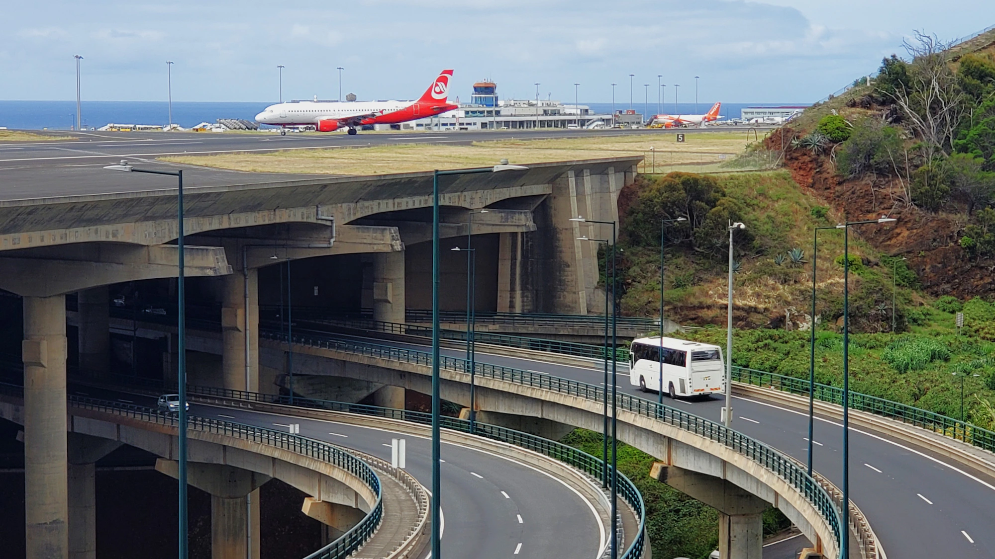 Aircraft on the runway at Funchal Airport, Madeira, with the coastal viaduct in the foreground