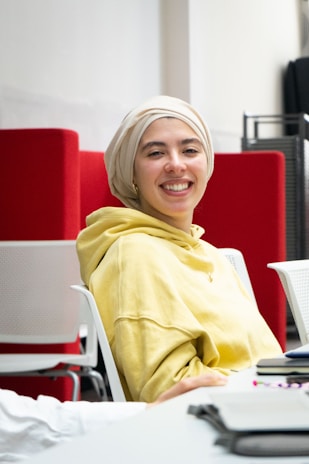 Syeda smiling warmly while filming a lifestyle vlog in her bright living room.