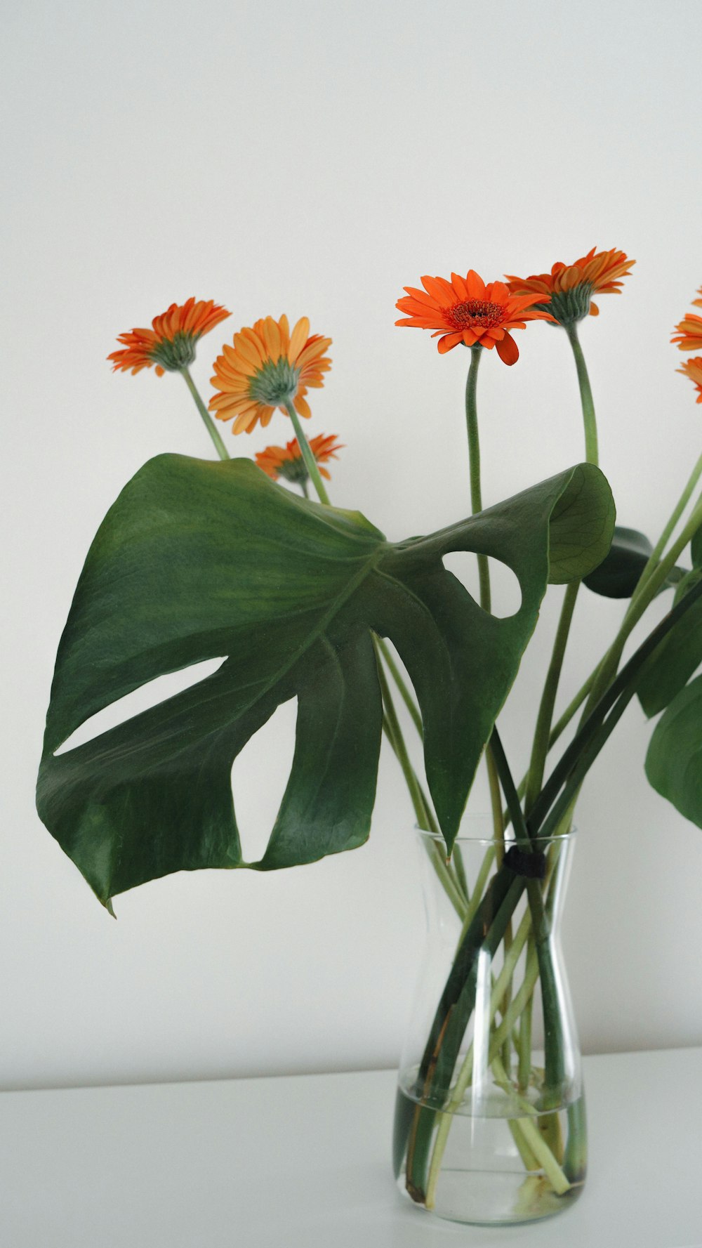 eine Vase gefüllt mit orangefarbenen Blumen auf einem Tisch