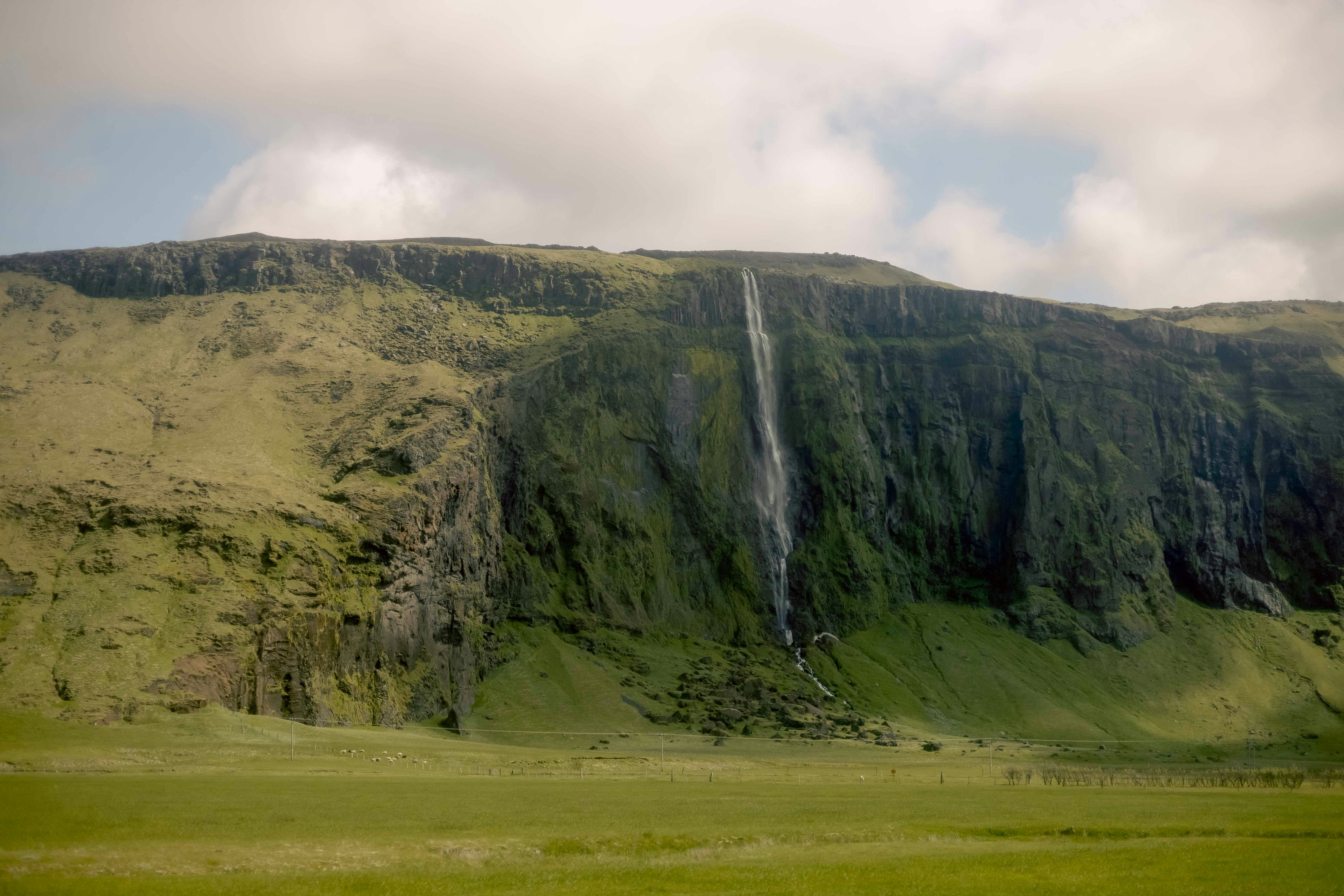 a large waterfall in the middle of a lush green field