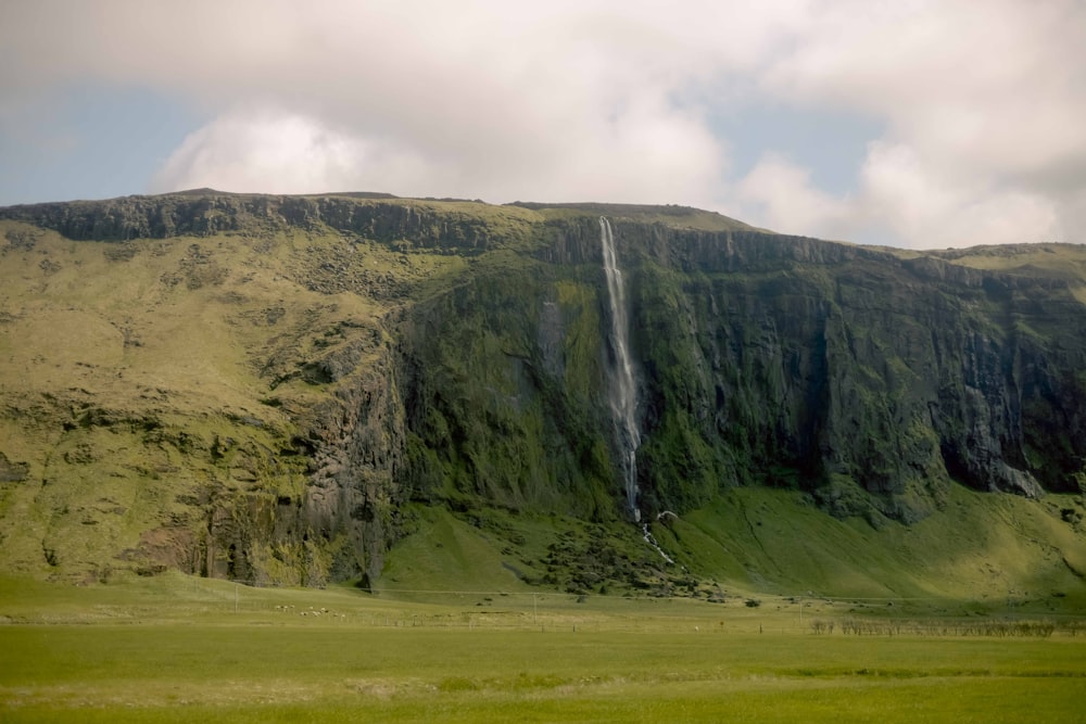 a large waterfall in the middle of a lush green field
