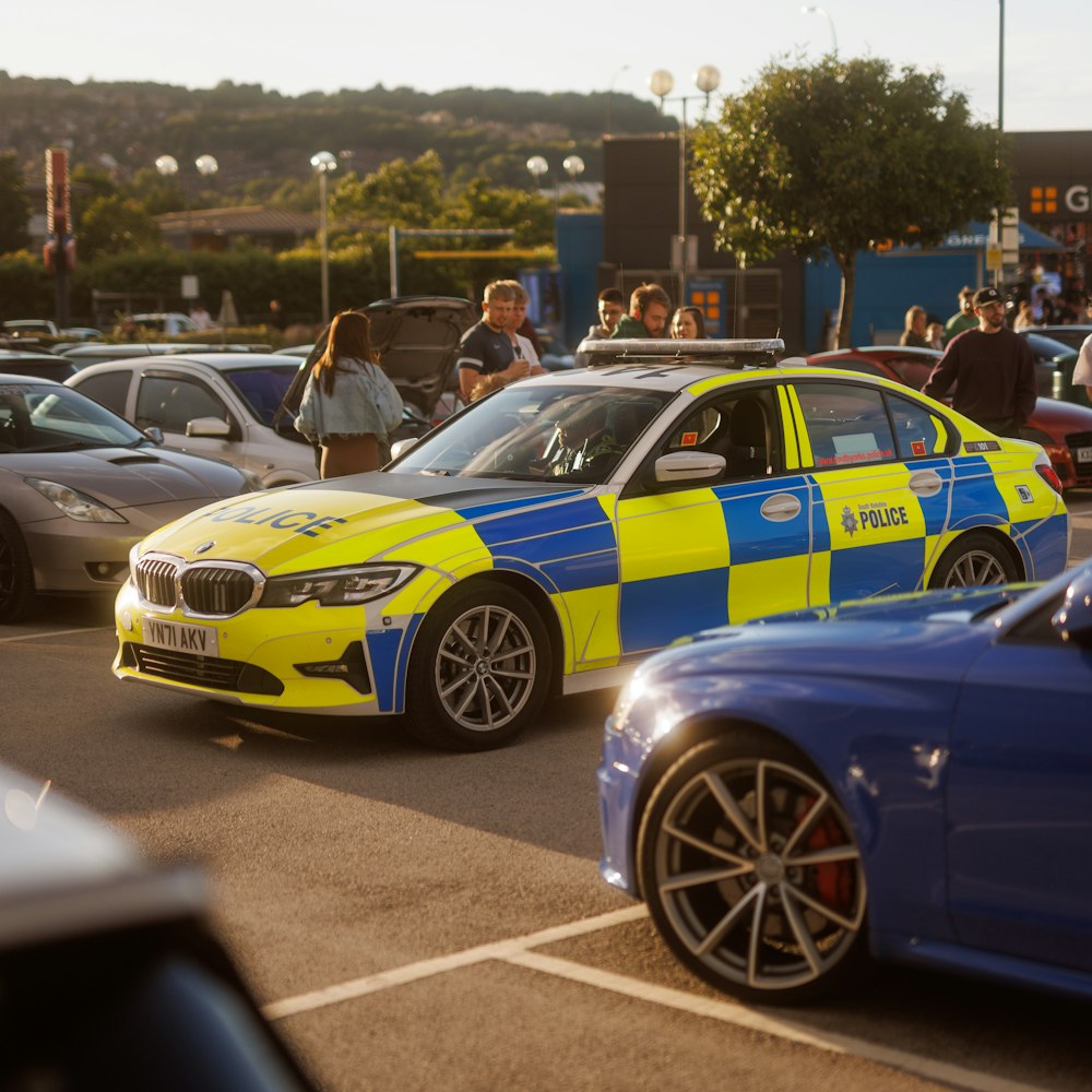 a yellow and blue police car driving down a street