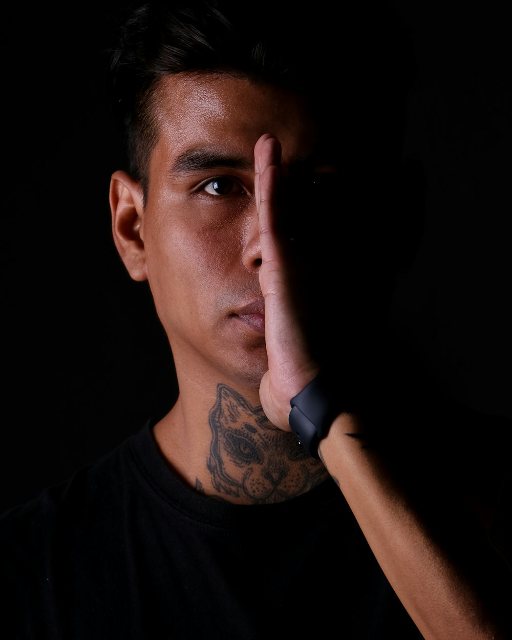 a man with a tattooed arm holding his hand up to his face