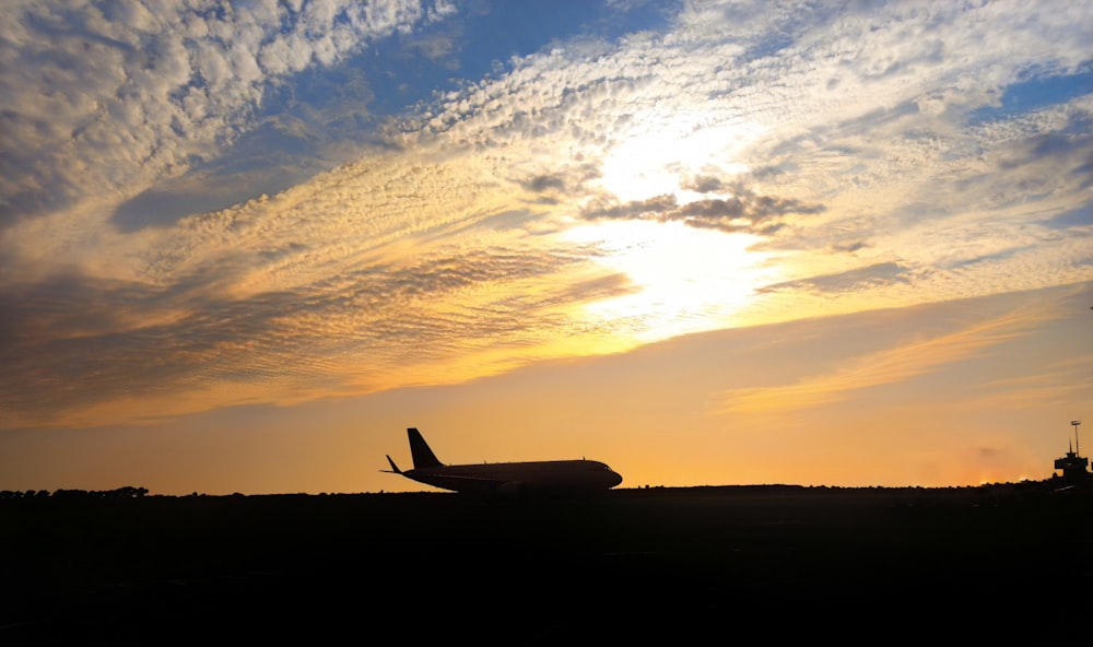 a plane is sitting on the runway at sunset