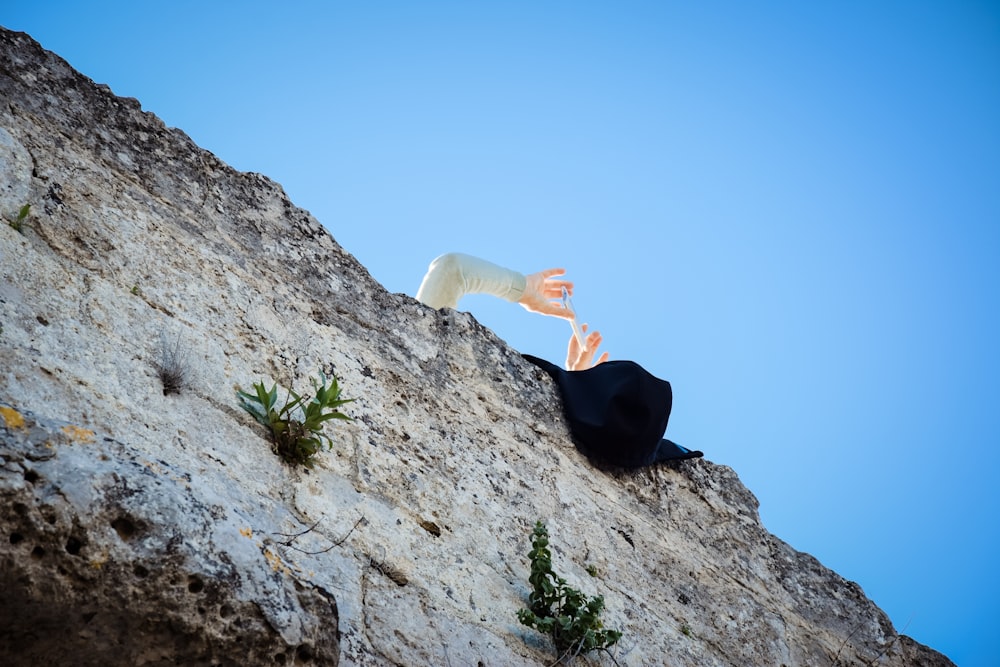 a person reaching up into the air from a cliff