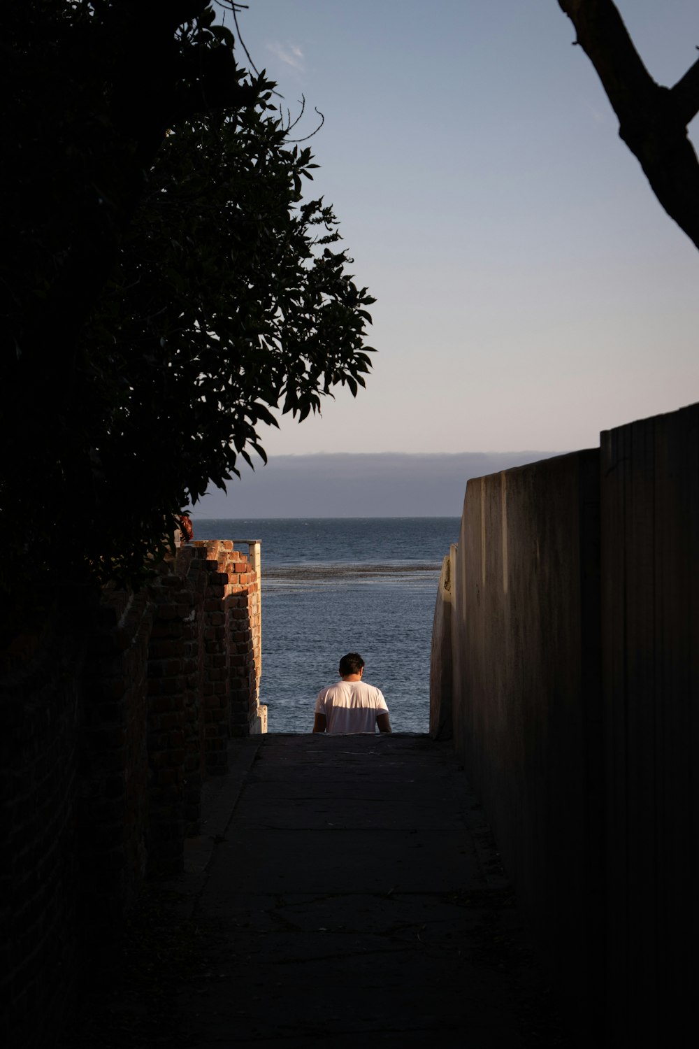 a person sitting on a wall looking out at the ocean