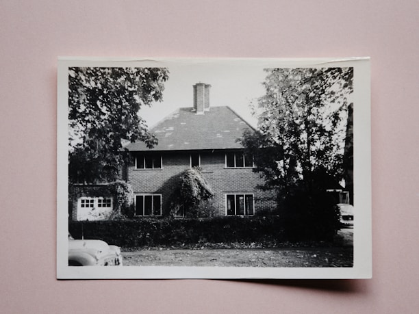Black and white photo of the house from the early 1900s surrounded by old trees.